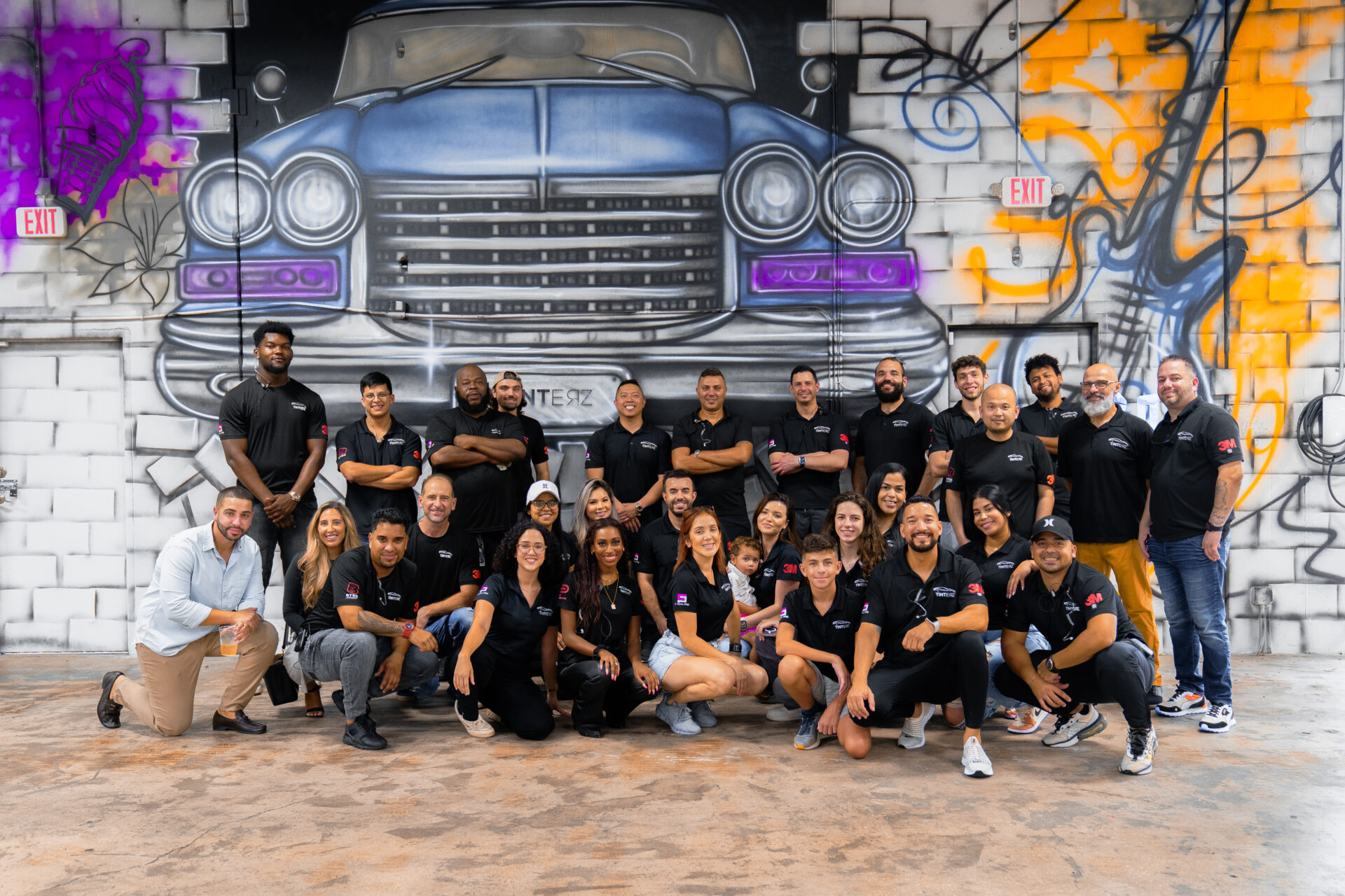The Tinterz install crew posed in front of a graffiti mural inside one of the bays
